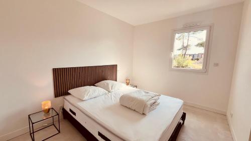 une chambre blanche avec un grand lit avec une fenêtre dans l'établissement La Tonka, maison neuve proche océan, à Saint-Jean-de-Monts
