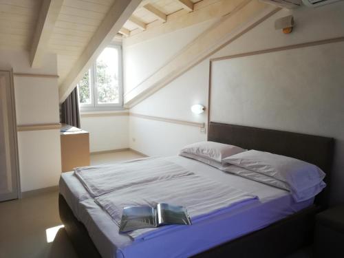 a bedroom with a bed with a book on it at Hotel Bogliaco in Gargnano