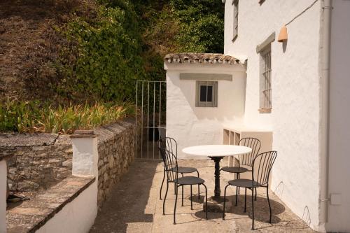 a table and chairs sitting next to a white building at Finca Luca Oliva in Zahara de la Sierra