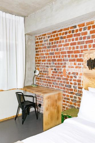 a bedroom with a desk and a brick wall at JAM Brussels in Brussels