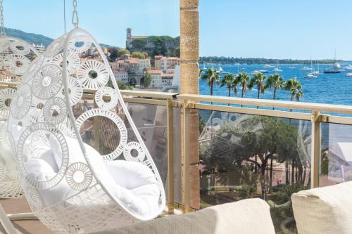 une chaise blanche sur un balcon avec vue sur l'eau dans l'établissement 1-Br Apartment on the Croisette Palais des Festivals, à Cannes