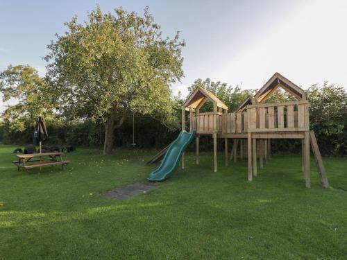 a playground with a slide in the grass at Willow in Kemble