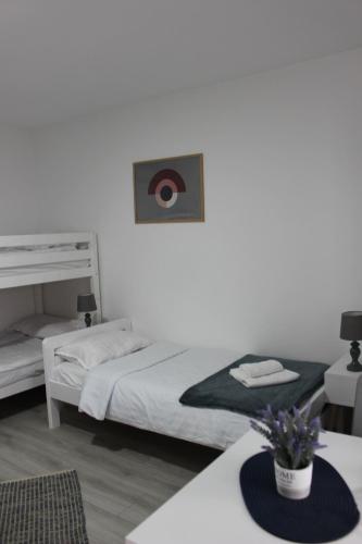 a white bedroom with a bed and a table at Temački konaci in Pirot