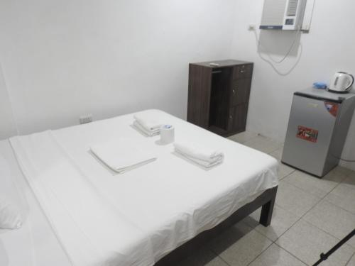 a hospital room with a white bed and a refrigerator at Pacifico Seaside Lodge in Moalboal