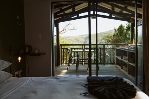 a bedroom with a bed and a balcony with a table and chairs at Matatane Camp - Babanango Game Reserve in Nkwalini