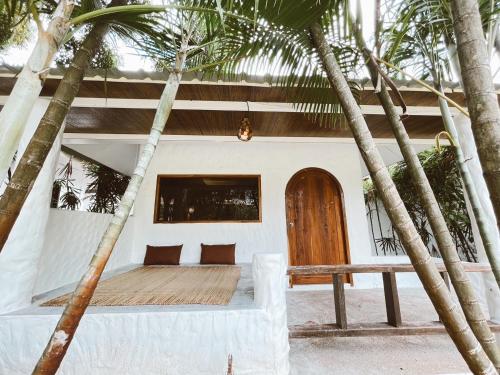 a house with a wooden door and palm trees at The Hub Erawan Resort in Chongsadao