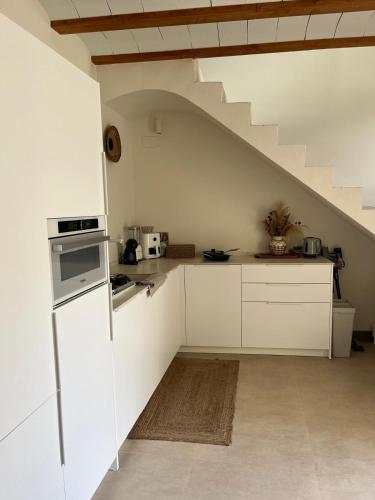 a kitchen with white cabinets and a staircase at Ca Erika in Aldaia