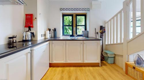 a kitchen with white cabinets and a window at The Sculptors Studio in Long Hanborough