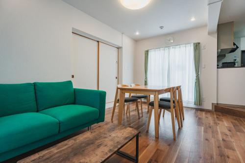 a living room with a green couch and a table at LT Shinjuku West in Tokyo