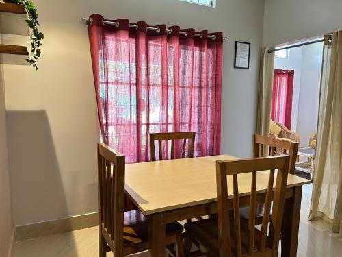 a dining room table with chairs and a red curtain at Sunny Villa in Sivasagar
