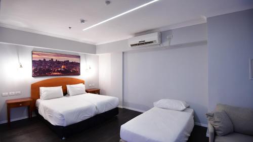 a hotel room with two beds and a couch at Spirit of Herzl Hotel הרוח של הרצל in Jerusalem