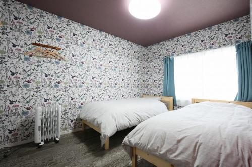 two beds in a bedroom with floral wallpaper at TR Niseko House Room Lavender in Niseko