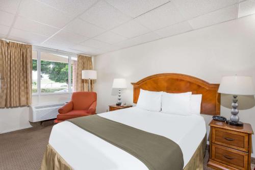 pokój hotelowy z łóżkiem i krzesłem w obiekcie Days Inn by Wyndham Bedford w mieście Bedford