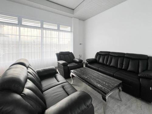 a living room with a leather couch and a table at RedDoorz Syariah at Prisma Homestay in Kalianget