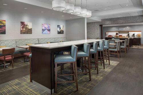 a restaurant with a bar with chairs and tables at Hampton Inn Haverhill in Haverhill