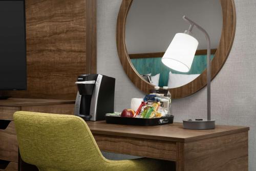 a desk with a mirror and a lamp and a chair at Hampton Inn Haverhill in Haverhill