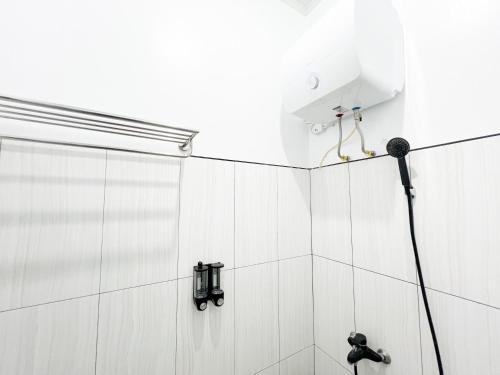 a bathroom with a shower with a microphone at RedDoorz Syariah at Prisma Homestay in Kalianget