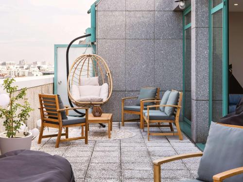eine Terrasse mit Stühlen und einer Schaukel auf dem Balkon in der Unterkunft Mercure Paris Saint-Ouen in Saint-Ouen