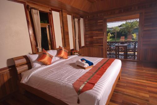 Schlafzimmer mit einem Bett und Blick auf einen Balkon in der Unterkunft Sangsawan Palace Khaolak Resort in Khao Lak