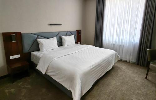 a bedroom with a large white bed with a blue headboard at Reikartz Qarshi in Qarshi