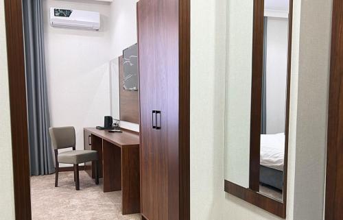 a bathroom with a mirror and a desk with a bed at Reikartz Qarshi in Qarshi
