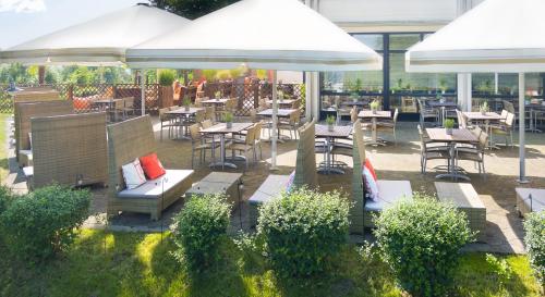an outdoor patio with tables and chairs and umbrellas at Mercure Hotel Bielefeld Johannisberg in Bielefeld