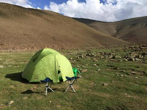 a green tent and two chairs in a field at Taghia Accommodation in Taghia