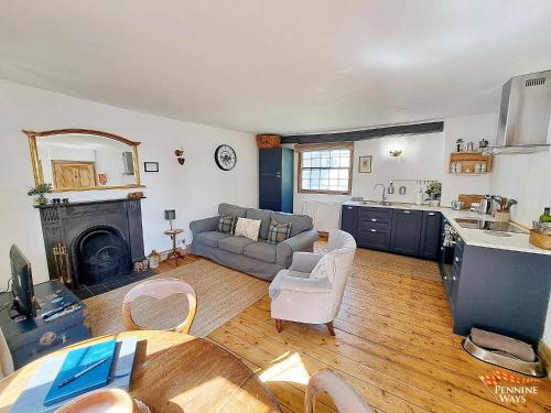 a kitchen and a living room with a couch and a table at Market House Apartment - Dog Friendly in Alston