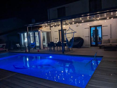a swimming pool in a house at night at Teresa Beauté - grande maison 4 chambres proche La Rochelle Ile de Ré avec piscine in Périgny