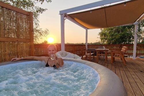 a woman in a hot tub with a glass of wine at Osada JurtCamp w Witowie in Witówko