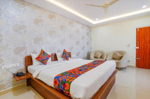a bedroom with a large bed and a chair at FabHotel Partha Residency - Kr puram in Bangalore