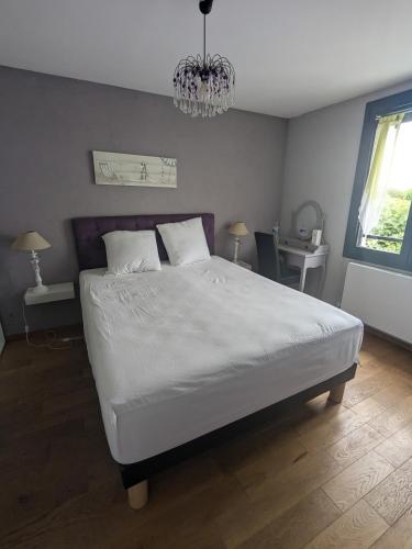 une chambre avec un grand lit blanc avec un lustre dans l'établissement Teresa Beauté - maison 3 chambres - 6 pers - proche La Rochelle, à Périgny
