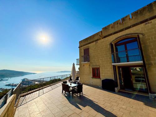 a building with a table and chairs on a balcony at Fort Chambray Holiday Villas & Apartments in Mġarr
