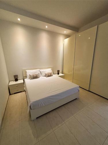 a bedroom with a white bed and two night stands at Fort Chambray Holiday Villas & Apartments in Mġarr