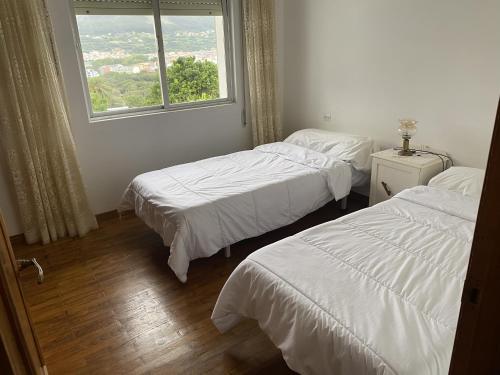 two beds in a room with a window at El Rincón de Oriona in Cedeira