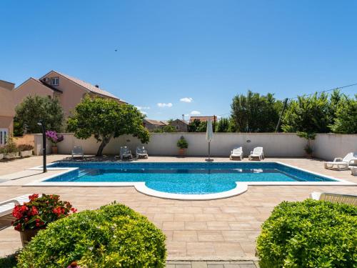 einen Pool in einem Garten mit Stühlen und Pflanzen in der Unterkunft Apartment Bonex-2 by Interhome in Privlaka