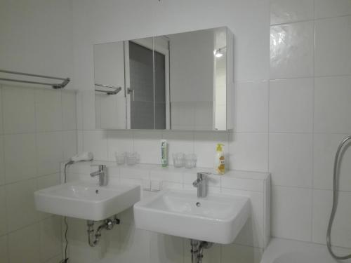 a white bathroom with two sinks and a mirror at Messezimmer Hannover / Private rooms for exhibitions in Hannover