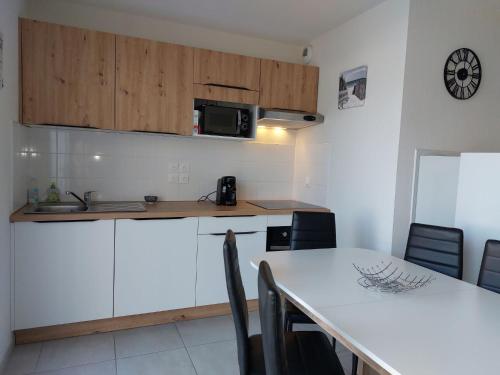 a kitchen with white cabinets and a table with chairs at Apartment SC C06 by Interhome in Mimizan