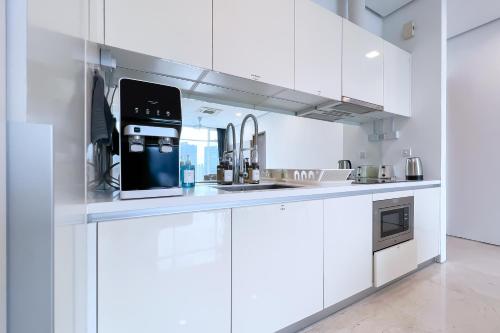a white kitchen with a sink and a microwave at Soho Suites KLCC by Leala in Kuala Lumpur