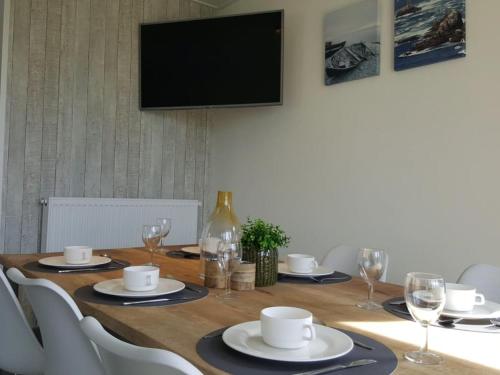 a wooden table with white chairs and a television on a wall at Holiday Home Long Beach by Interhome in Retranchement