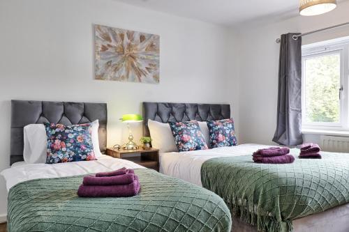 zwei Betten in einem Schlafzimmer mit lila Handtüchern darauf in der Unterkunft Stylish 3 bedroom House In Grt Gregorie Basildon & Essex - Free Wifi, Parking, Dedicated Office & Private Garden in Basildon