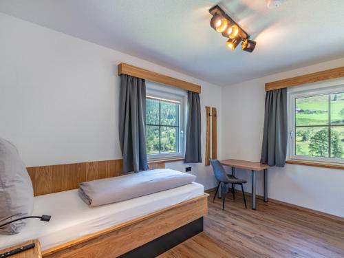 a bedroom with a bed and a desk and windows at Apartment Grimming by Interhome in Kleinsölk