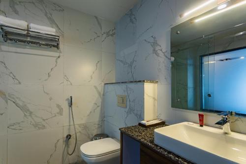 a bathroom with a sink and a toilet and a mirror at River Bank Jungle Resort, Chitwan in Bharatpur