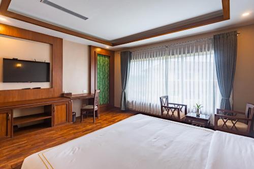 a hotel room with a bed and a flat screen tv at River Bank Jungle Resort, Chitwan in Bharatpur