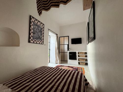 a bedroom with a bed in a room with a tv at Riad Ait El Mouden in Agadir