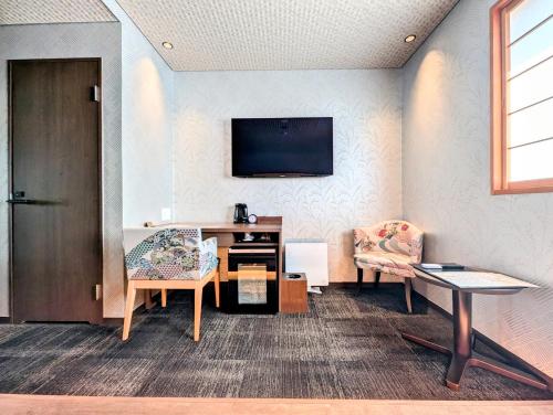 a room with two chairs and a tv on a wall at ひがし茶屋街らしく金沢 Hotel Rashiku kanazawa in Kanazawa