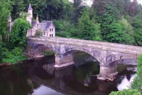 a bridge over a river in front of a castle at The Orchard Apartment, Clyde Valley in Dalserf