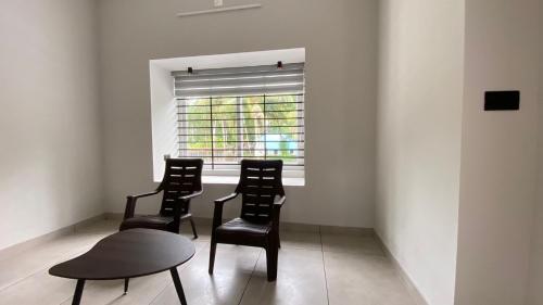 a room with two chairs and a table and a window at Peaceful and Serene Space in Andūrkonam