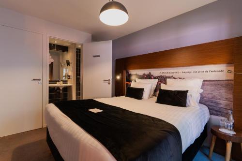 a bedroom with a large bed with a wooden headboard at Best Western Hôtel Garden and Spa in La Baule