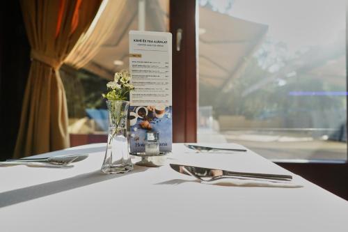 a table with a vase of flowers on a table at Bassiana Hotel és Étterem in Sárvár